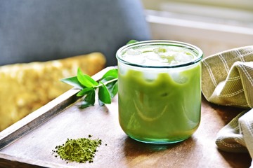 Glass of iced matcha green tea latte on the light home background 