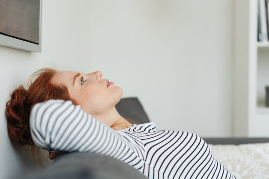 Young woman deep in thought relaxing on a sofa