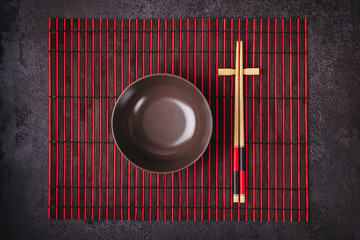 Asian Japanese table setting. Bamboo chopsticks and bowl on striped mat