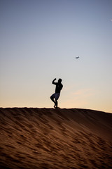 Dark silhouette of a man walking at the desert dunes and boxing. Dawn time