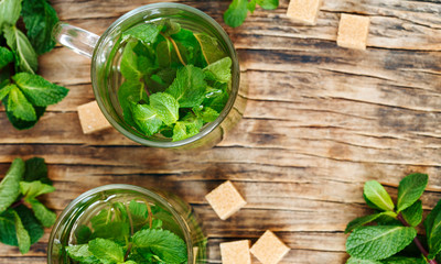 Cup of mint tea on wooden background, top view, copy space