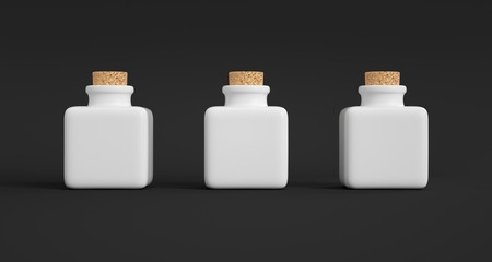 Three square porcelain pots with a cork stopper. Dark background