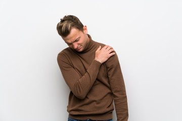 Blonde man over isolated white wall suffering from pain in shoulder for having made an effort