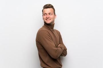 Blonde man over isolated white wall with arms crossed