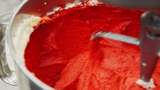 Close up slow motion shot of stand mixer whipping red velvet creamy batter for cupcakes or cake