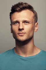 Obraz premium Male beauty, boy next door concept. Portrait of smiling and confused 30-year-old man standing over grey background. Close up. Classic style. Wavy glossy blond hair. Studio shot