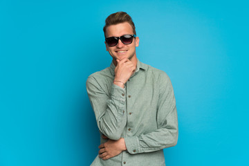 Fototapeta premium Blonde man over isolated blue wall with glasses and smiling
