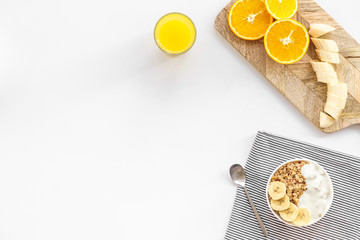 granola with banana slices and orange juice for breakfast on blue background top view copyspace