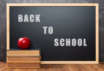 books and apple in front of a black board written with BACK TO SCHOOL, THE  WORDS WITH CLIPPING PATH AND CAN BE DELETED DIRECTLY