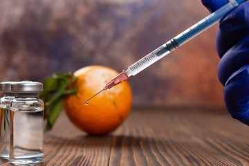 medical syringe and bottles of vaccine with a moldy orange on background