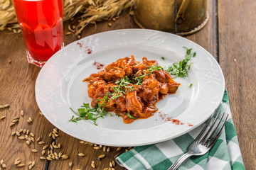 plate of delicious authentic Hungarian goulash with berry drink on wooden table