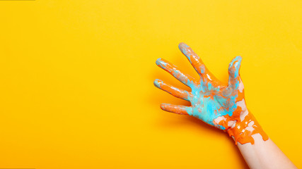 female hand in the paint color mixing on a yellow background, creative idea of advertising, palm...