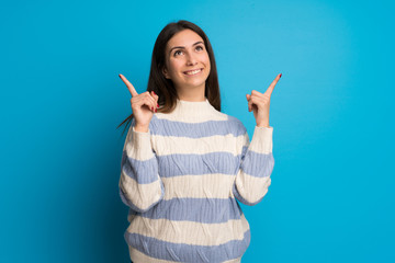 Young woman over blue wall pointing with the index finger a great idea