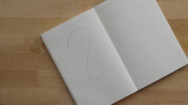 Guy write one large question sign at blank page of notepad, top down shot