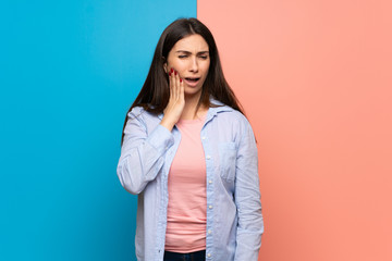 Young woman over pink and blue wall with toothache