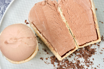 Chocolate ice cream in a waffle with chocolate chips on a white plate.