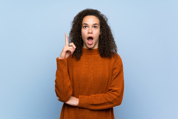 Dominican woman with curly hair thinking an idea pointing the finger up