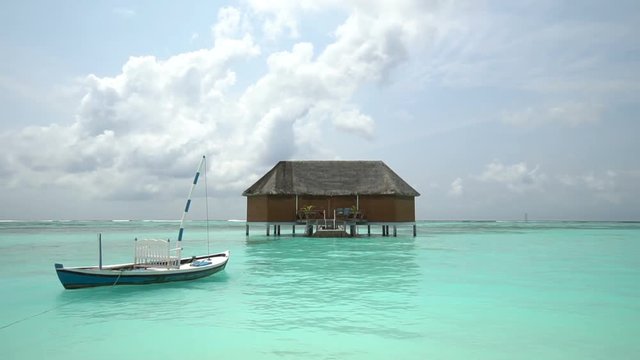 Vacation- Landscape view of beach with exotic wooden house (hut) with a boat on the seas. view of a beach,clouds beautiful sky .