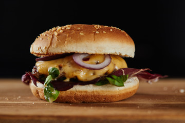 delicious burger with meat, cheese and onions isolated on black