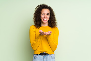 Dominican woman over isolated green background holding copyspace imaginary on the palm to insert an...