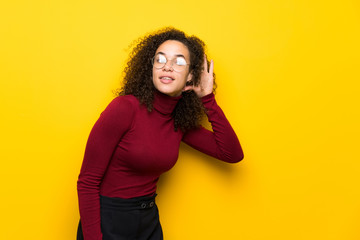 Dominican woman with turtleneck sweater listening to something by putting hand on the ear