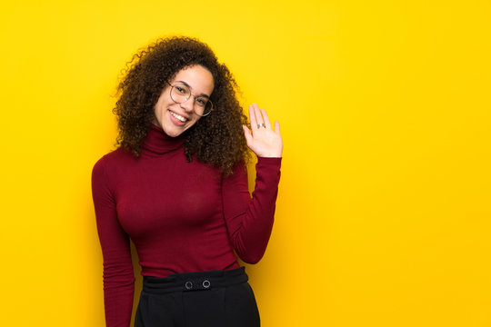 Dominican woman with turtleneck sweater saluting with hand with happy expression