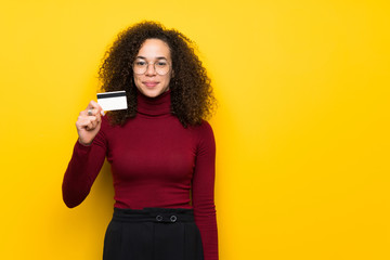 Dominican woman with turtleneck sweater holding a credit card