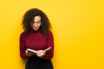 Dominican woman with turtleneck sweater holding a book and enjoying reading