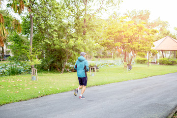 Unidentified middle aged man jogging in the park in morning.