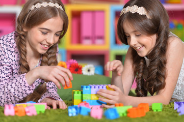 Two girls playing with colorful plastic blocks