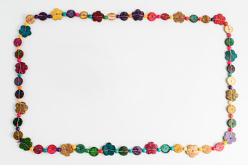 Frame of multi coloured beads hand made from coconut shell, flowers and rounded pieces, traditional African decoration isolated on white background, top view, flat lay