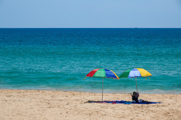 Two colorful umbrellas on white sand beach.