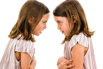 Identical twin girls sisters are arguing yelling at each other.