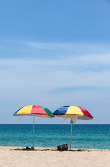 Fototapeta na wymiar Two colorful umbrellas on white sand beach.
