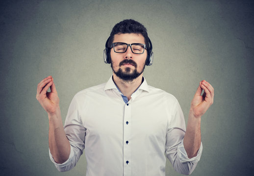 man in headphones with closed eyes listening to music and meditating