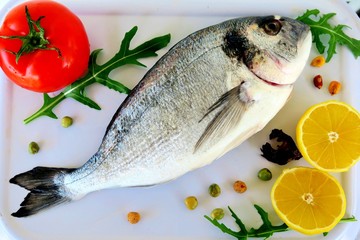 sea fish with spices, red tomatoes, lemon and herbs