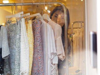 Beautiful Asian woman shopping for new dress and clothings inside a store.Selected focus.