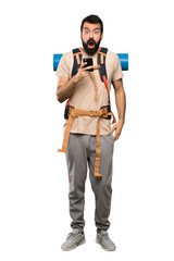 Hiker man surprised and sending a message over isolated white background