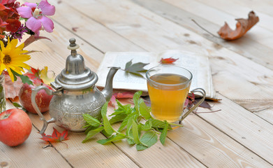 cup of mint tea with flowers and mint leaf on a table