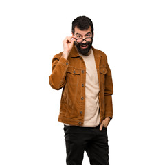 Handsome man with beard with glasses and surprised over isolated white background