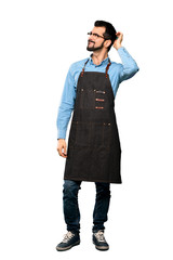 Full-length shot of Man with apron having doubts while scratching head over isolated white background