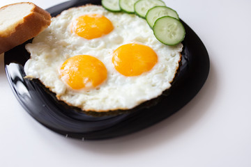Breakfast. Fried eggs with bread and cucumbers