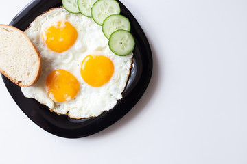 Breakfast. Fried eggs with bread and cucumbers