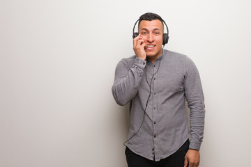 Young latin man listening to music biting nails, nervous and very anxious