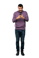 Full-length shot of Handsome man with sweatshirt surprised and sending a message over isolated white background