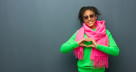Young african american girl with blue eyes doing a heart shape with hands