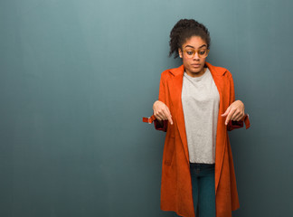 Young black african american girl with blue eyes pointing down