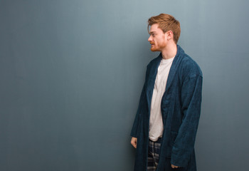 Young redhead man in pajama on the side looking to front