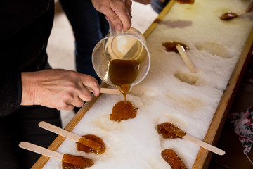 Making maple candy on snow in a maple sugar camp in New Brunswick