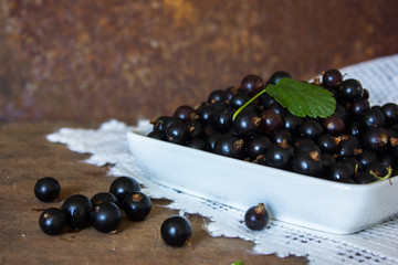 Fresh currants in bowl / Top view red ripe black currant fruit and green leaf on metal background